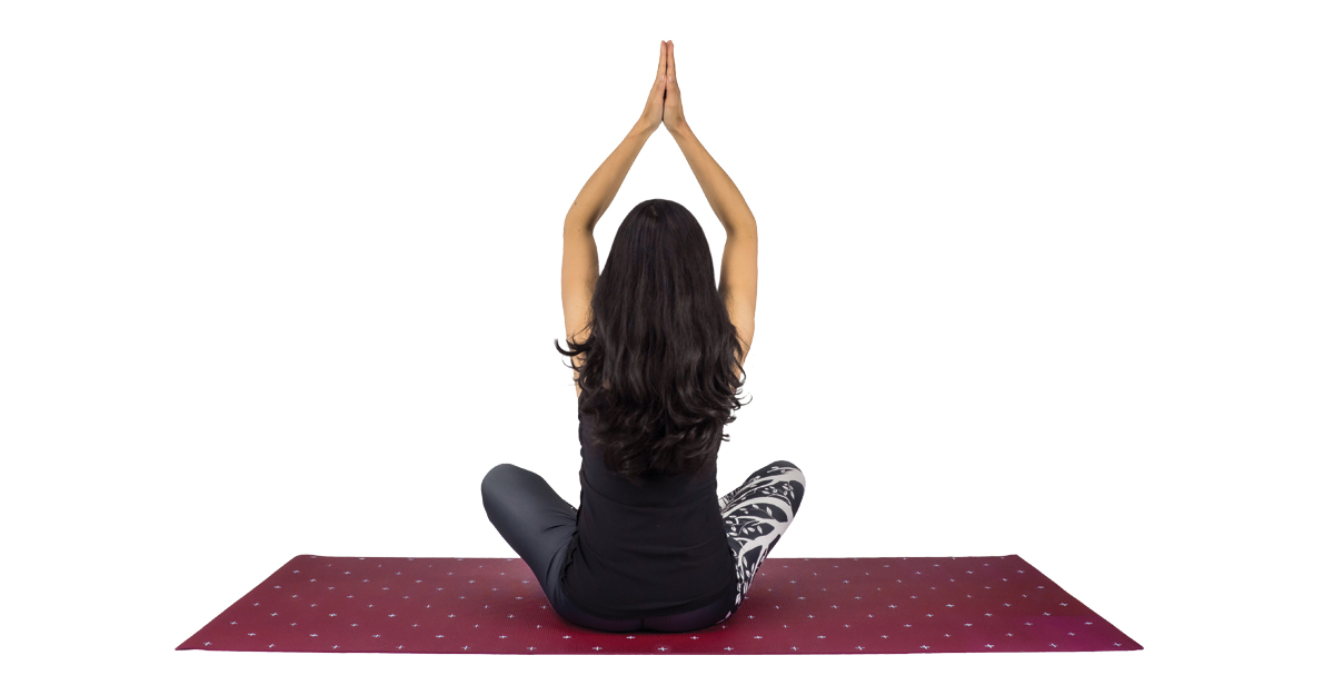 Isolated woman on white sitting on yoga mat with hands together